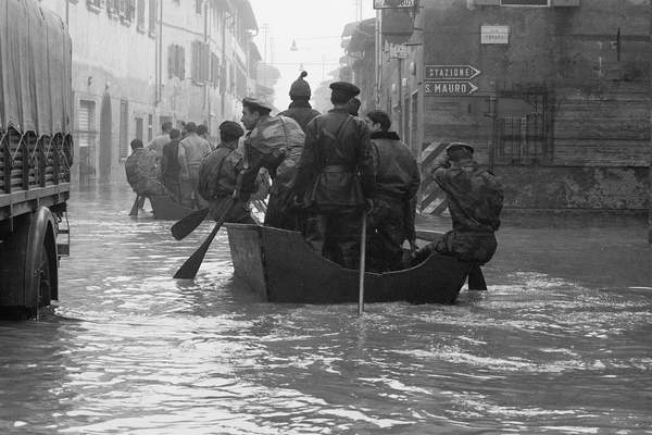 Soldiers rowing on a small boat rescuing people stranded by the flood of Florence, November 1966 (b/w photo)