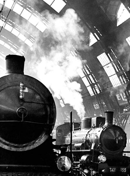 old locomotives with steam coming out inside a station in Italy, black and white photo